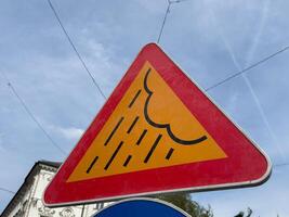 Triangular weather warning sign with rain cloud symbol on clear day photo