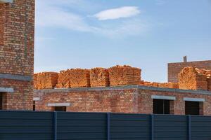 Workers prepare a construction site with new brick structures, with stacks of bricks visible against a bright blue sky photo