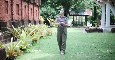 Handheld shot, Happy Asian woman is enjoying a quiet stroll, taking photos of old sculptures and ancient brick structures, Enjoy holiday travel. video