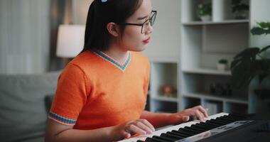 Asian woman is relaxing and enjoy playing music on an electronic keyboard in a quiet house. Leisure activities at home video