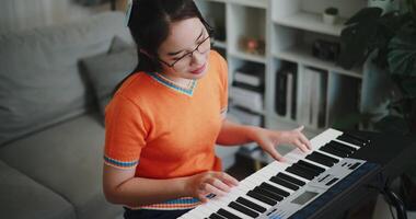 Handheld high angle view shot, Beautiful woman playing the keyboard with happy smile in cozy living room. Enjoy a relaxing weekend activity video