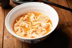 Yellow Croaker Wontons in Rich Golden Soup in bowl side view of Traditional Chinese Dish photo