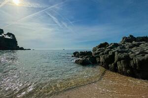 A stunning beach landscape in Lloret de Mar, Spain, with clear blue skies and visible airplane trails. The perfect summer scene with space for text or copy. photo