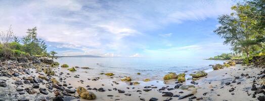Rocky Tropical Beach Under Blue Sky. Scenic Coastal View on Remote Tropical Shoreline photo