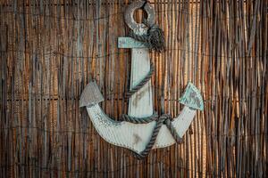 Rustic anchor adorned with frayed rope against a woven backdrop creates an inviting coastal atmosphere in this charming nautical decor photo