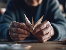 Hands folding paper crane origami, creative focus, peaceful atmosphere, wooden table surface photo
