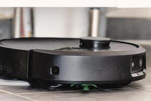 Robot vacuum cleaner with dust, real life photo, saves time and goes into hard-to-reach places, helper photo