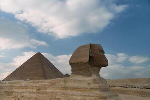 The iconic Great Sphinx and Pyramid stand majestically beneath a dramatically cloudy sky photo