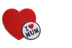 Horizontal photo of handmade red heart embroidery with I LOVE MUM text inside circle, set on white background with copy space. Perfect for Mother Day greeting.