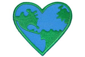 Horizontal photo of heart shaped world embroidery in green and blue thread on white background. Perfect for earth day, eco friendly and global warming themes.