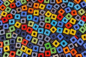 Horizontal close-up of colorful square paving stones with round holes, arranged in alternating directions. Modern abstract pattern background for creative design. photo