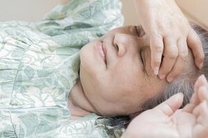 Close-up view head shot close up older woman lying in bed at home, covering eyes with arm, trying falling asleep. photo