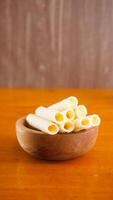 Crispy rolled wafer snack filled with sweet cheese cream on serving plate isolated on wooden background photo