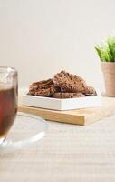 Chocolate cookies treats on a white plate with a cup tea isolated on wooden textured background photo