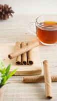 Delicious chocolate wafer roll on a wooden board with a cup of tea for enjoyment isolated on wooden textured background photo