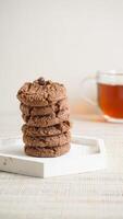 Stack of delicious chocolate cookies on a white plate isolated on light background photo