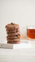 Stack of chocolate cookies on a white plate isolated on light background photo