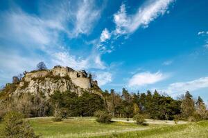 Bottom view of a hill with the ruins of the Hohentwil castle on its top against a blue sky photo
