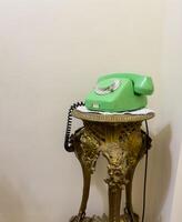 Old green phone is sitting on a gold stand. USSR phone photo