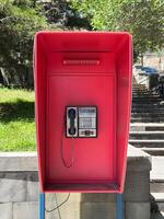 A red phone booth with a phone inside photo