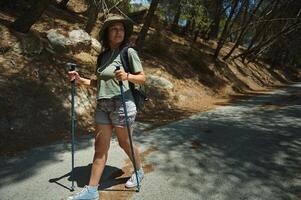 Woman Enjoying a Nature Hike with Walking Poles in a Forested Area on a Sunny Day photo