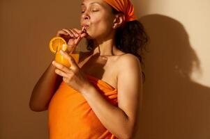 A Relaxed Woman Enjoying Fresh Orange Juice in Warm Toned Setting photo