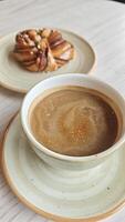 Cup of hot coffee served with a traditional Swedish cinnamon bun on a rustic plate. This image represents a cozy fika moment and Scandinavian coffee culture concept photo