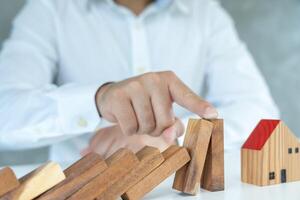 hands protect domino, Businessman hands stop dominoes falling in house crisis. business risk control and planning and strategies to run prevent insurance businesses. photo