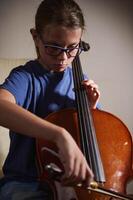 Young Girl Practicing the Cello at Home While Wearing Glasses photo