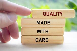 Quality made with care text on wooden blocks being gently pushed by hand represents thoughtful, intentional craftsmanship photo