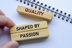 Quality shaped by passion text on wooden blocks over a notepad reflects teamwork driven by genuine enthusiasm photo