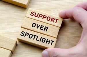 Support over spotlight text on wooden block. photo