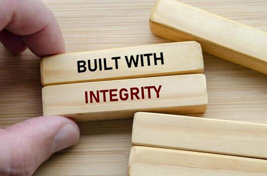 Built with integrity text on wooden blocks held by hand reflects trust, strength, and ethical values in every action photo