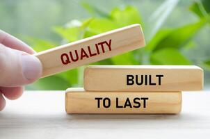 Quality Built to last text on green wooden blocks held by hand represents durability and long-term reliability photo