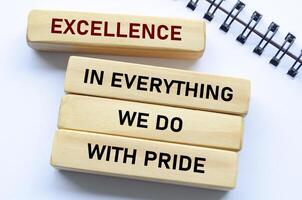Excellence in everything we do with pride text on wooden blocks and notebook reflects unwavering quality and pride in every action photo