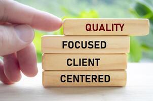 Quality focused client centered text on wooden blocks held by hand showcases a dedication to understanding and serving clients photo