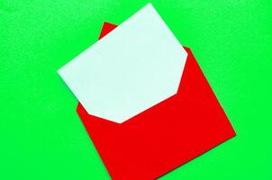 Top view of white notepad with envelope on green cover background with customizable space for text or ideas photo