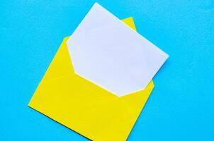 Top view of white notepad with envelope on blue cover background with customizable space for text or ideas.. photo