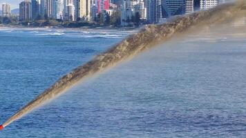 Sand is pumped into the ocean near a city skyline, illustrating coastal erosion management under clear skies video