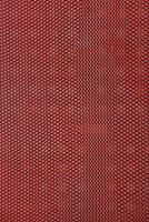 Close-up of a textured red rubber mat with repeating triangle pattern and dark background photo