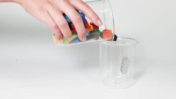Hands moving colorful blocks from one jar to another video