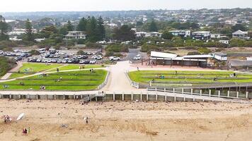 Aerial footage captures people enjoying Ocean Grove's beachfront, showcasing vibrant activity and scenic views under natural lighting video