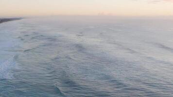 Aerial view of gentle ocean waves during sunrise at Gold Coast, Australia. Soft lighting creates a tranquil atmosphere video