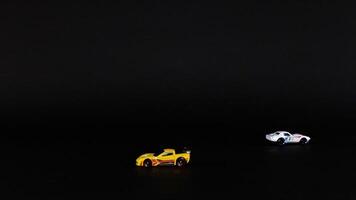 Two toy cars moving across a dark background video