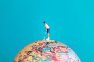 A miniature figure of a golfer playing on top of a globe photo