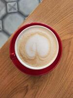 Cappuccino with Heart Latte Art in Red Cup on Table photo