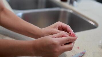 Hands delicately extract caviar from finger lime in a well-lit kitchen environment, showcasing culinary preparation video