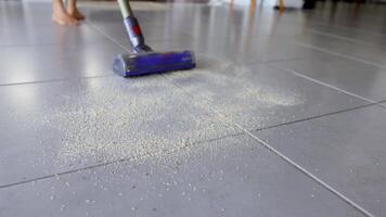 A vacuum cleaner removes crumbs from kitchen tiles in a well-lit home environment, demonstrating effective cleaning techniques video