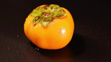 A persimmon rotates on a dark background video