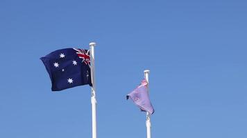 Two Australian flags fluttering against a clear sky video